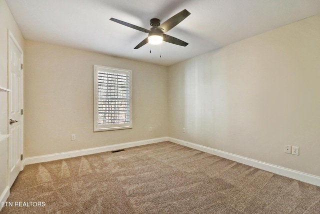 carpeted spare room featuring visible vents, baseboards, and ceiling fan