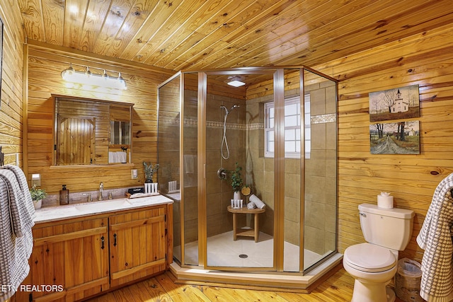 bathroom with vanity, toilet, an enclosed shower, and wood walls