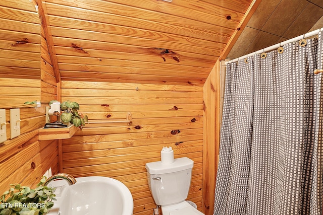 bathroom with wooden ceiling, toilet, sink, and wood walls