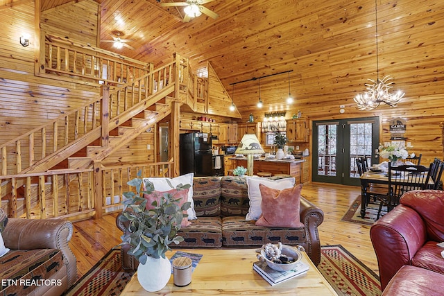 living room featuring wood ceiling, high vaulted ceiling, wooden walls, light hardwood / wood-style floors, and ceiling fan with notable chandelier