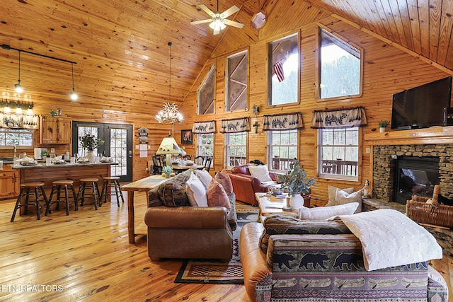 living room with a wealth of natural light, light hardwood / wood-style flooring, a fireplace, and wood walls