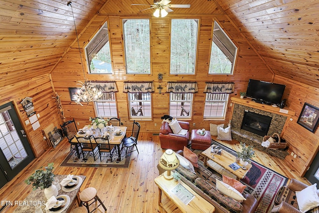 living room with hardwood / wood-style floors, high vaulted ceiling, wooden walls, a fireplace, and wooden ceiling