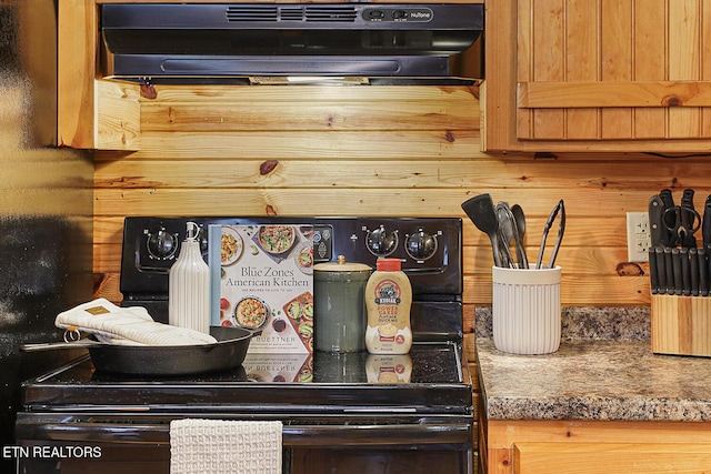 interior details with dark stone countertops and black range with electric cooktop