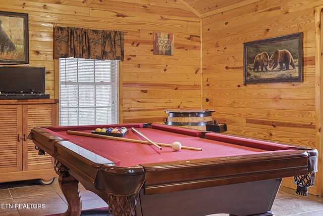 recreation room featuring tile patterned floors, vaulted ceiling, and wood walls