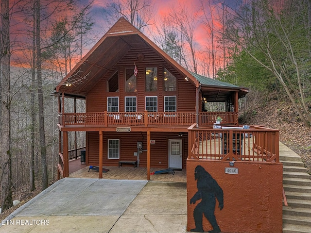 log-style house featuring a wooden deck and a patio