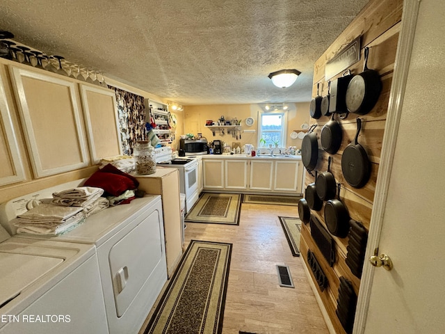 interior space with sink, washing machine and dryer, a textured ceiling, and electric range