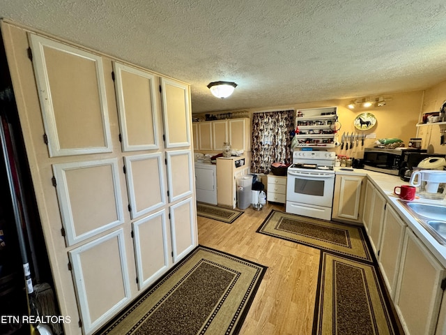 kitchen with washing machine and dryer, light wood-type flooring, a textured ceiling, and electric range