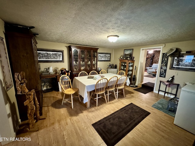 dining space with light hardwood / wood-style flooring and a textured ceiling