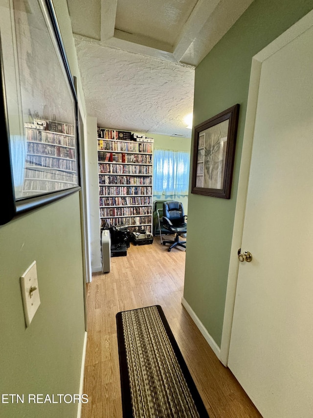 corridor featuring light hardwood / wood-style flooring and a textured ceiling