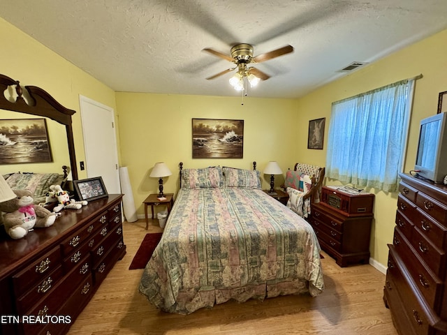 bedroom with ceiling fan, a textured ceiling, and light hardwood / wood-style flooring