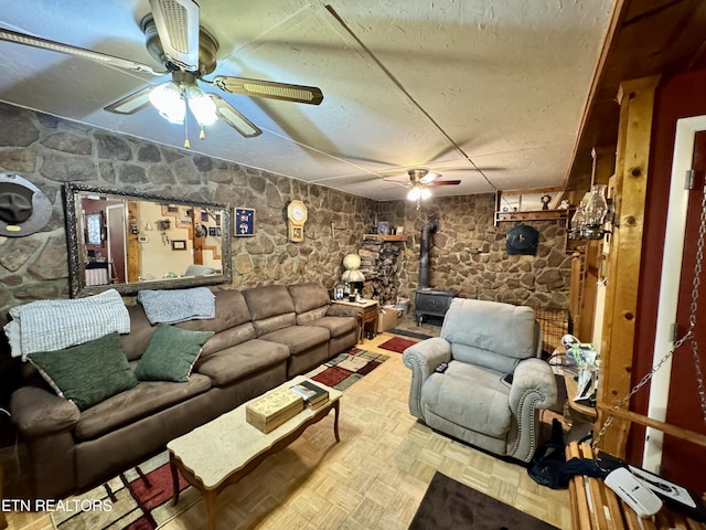 living room with a wood stove, parquet floors, and ceiling fan