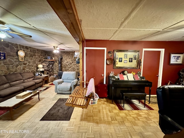 living room featuring ceiling fan, light parquet floors, and a wood stove