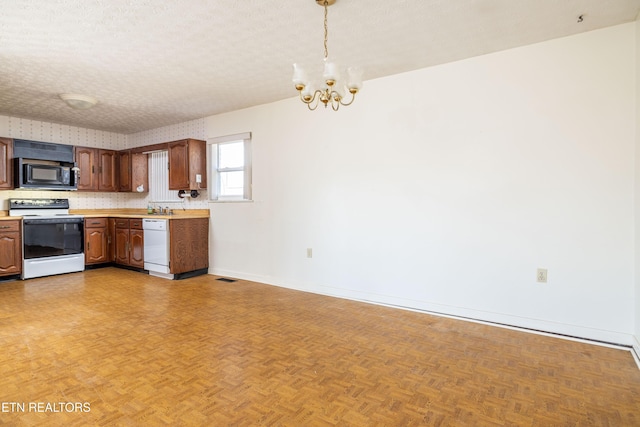 kitchen featuring decorative light fixtures, a textured ceiling, parquet floors, a notable chandelier, and white appliances