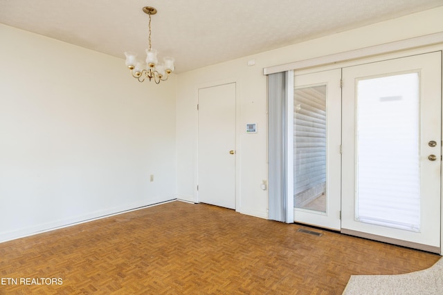 unfurnished room featuring parquet floors, a notable chandelier, and a textured ceiling