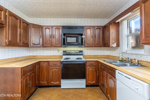 kitchen featuring sink, white appliances, a textured ceiling, and light parquet floors