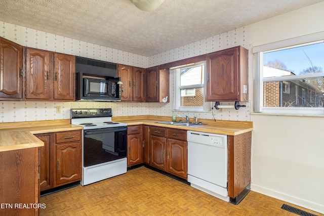 kitchen with white appliances, sink, a textured ceiling, and light parquet floors