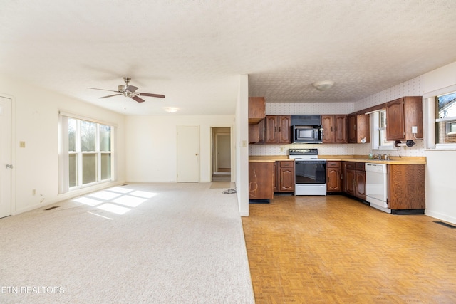 kitchen with sink, white appliances, ceiling fan, light parquet floors, and a textured ceiling