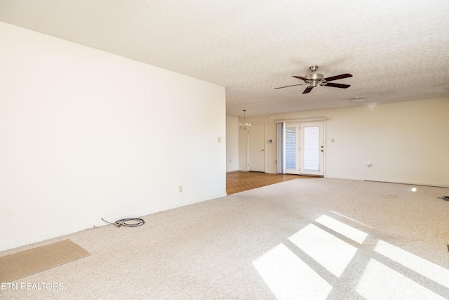 empty room featuring carpet flooring, ceiling fan with notable chandelier, and a textured ceiling