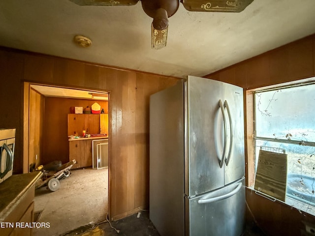 kitchen featuring stainless steel fridge and wood walls