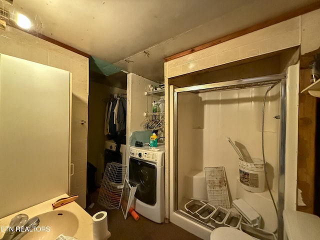 bathroom featuring washer / clothes dryer and a shower with door