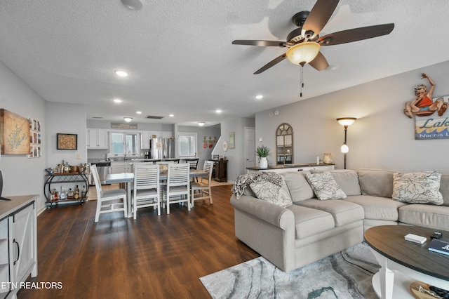 living room with ceiling fan, dark hardwood / wood-style flooring, sink, and a textured ceiling