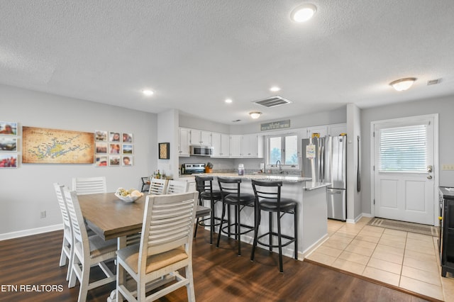 dining room featuring sink, light hardwood / wood-style floors, and a textured ceiling