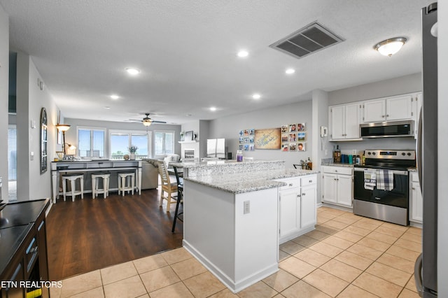 kitchen with white cabinetry, stainless steel appliances, a kitchen island, and light tile patterned floors