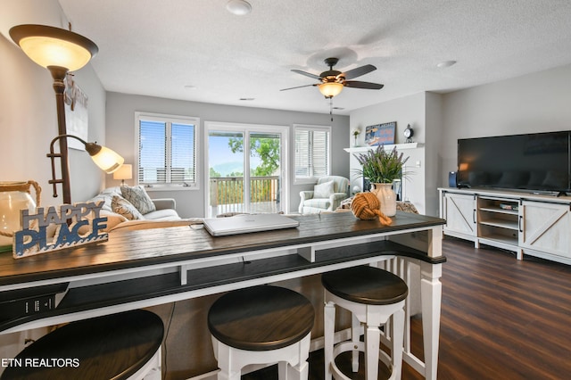 kitchen featuring ceiling fan, dark hardwood / wood-style floors, a textured ceiling, and a kitchen breakfast bar