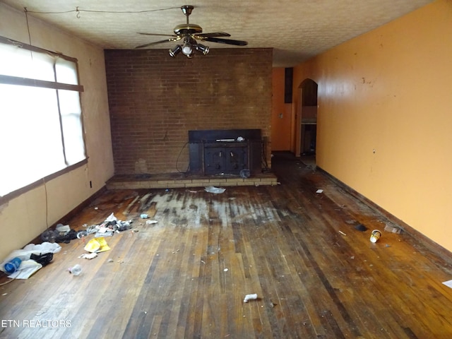 unfurnished living room with ceiling fan, a textured ceiling, and dark hardwood / wood-style flooring