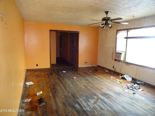 empty room featuring cooling unit, ceiling fan, dark hardwood / wood-style floors, and a textured ceiling