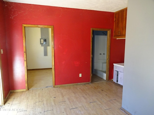 unfurnished dining area featuring electric panel, light wood-style flooring, and baseboards