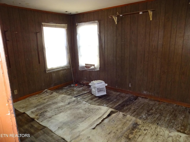 empty room featuring wooden walls, baseboards, and dark wood finished floors