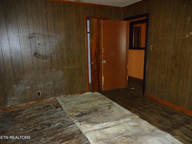 bedroom featuring a closet, dark wood finished floors, and wood walls