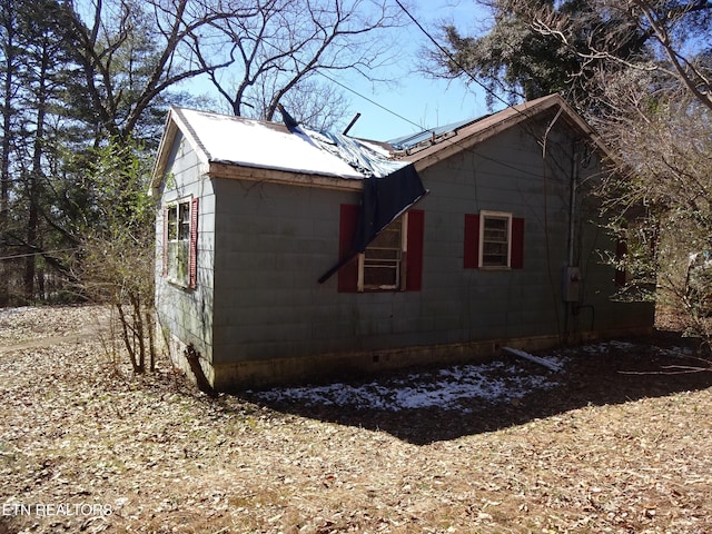 view of home's exterior with concrete block siding and metal roof