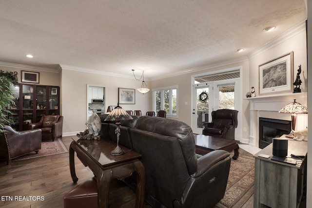 living room featuring hardwood / wood-style flooring, ornamental molding, and a textured ceiling