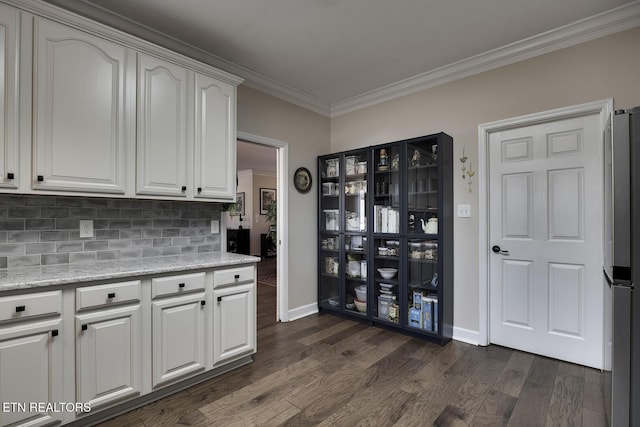 kitchen with crown molding, stainless steel fridge, white cabinetry, dark hardwood / wood-style floors, and light stone counters