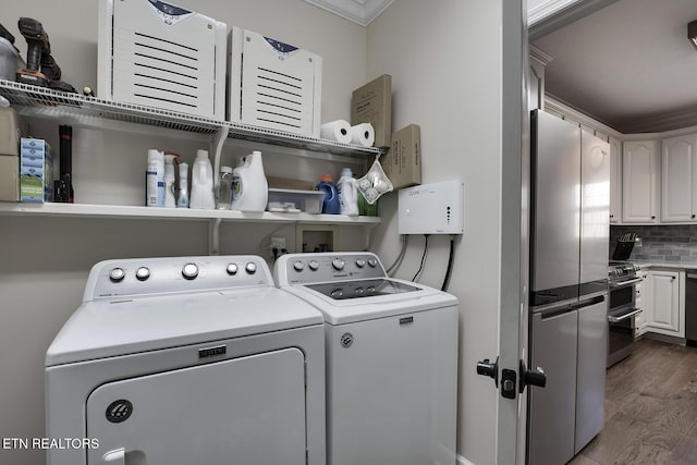 washroom featuring crown molding, dark wood-type flooring, and washing machine and dryer