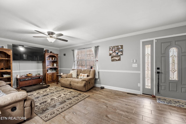 living area featuring ceiling fan, crown molding, baseboards, and wood finished floors