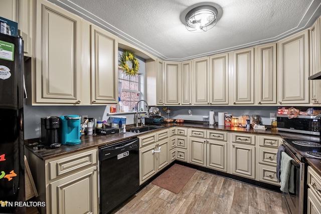 kitchen featuring black appliances, cream cabinetry, and a sink