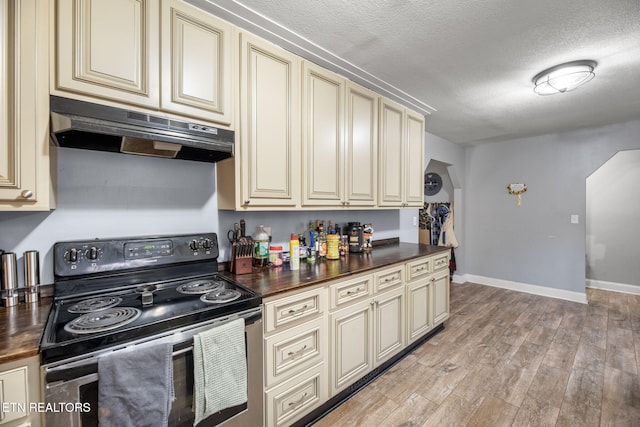 kitchen featuring under cabinet range hood, stainless steel range with electric stovetop, and cream cabinets