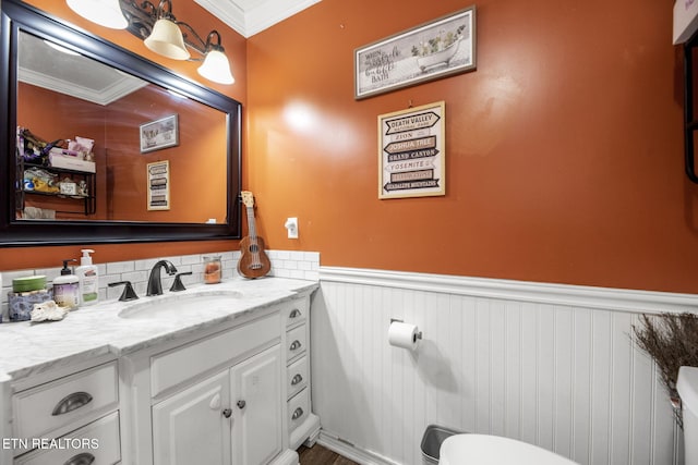 half bathroom featuring a wainscoted wall, vanity, and ornamental molding