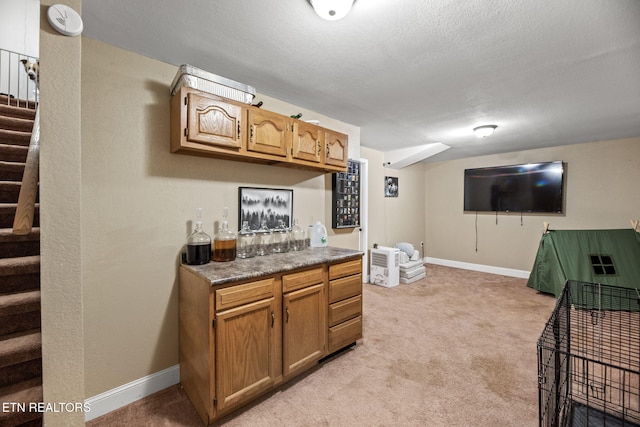 bar with light colored carpet, a textured ceiling, stairs, and baseboards