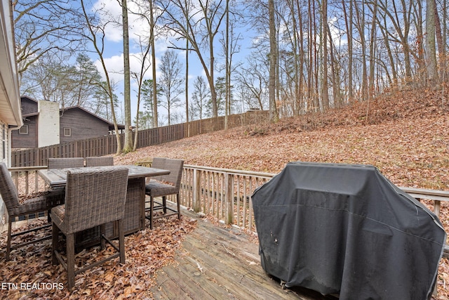 wooden terrace featuring grilling area, outdoor dining area, and fence