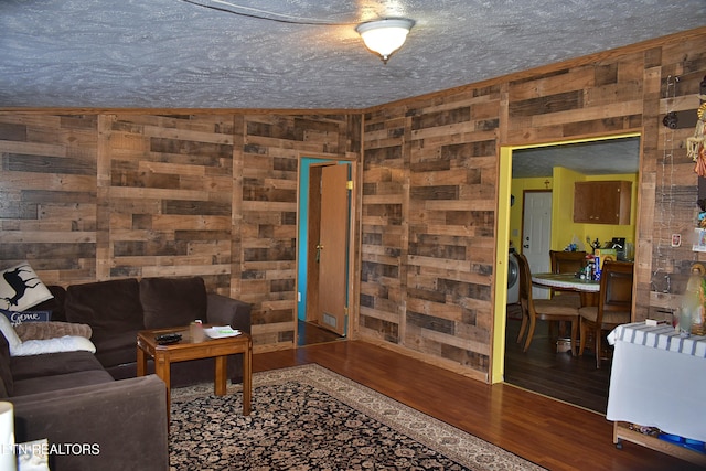 living room featuring dark hardwood / wood-style floors, wooden walls, and a textured ceiling