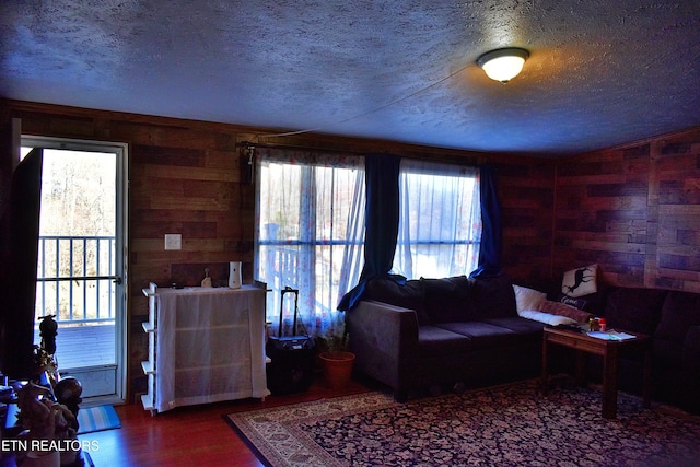 living room with hardwood / wood-style floors, plenty of natural light, wooden walls, and a textured ceiling