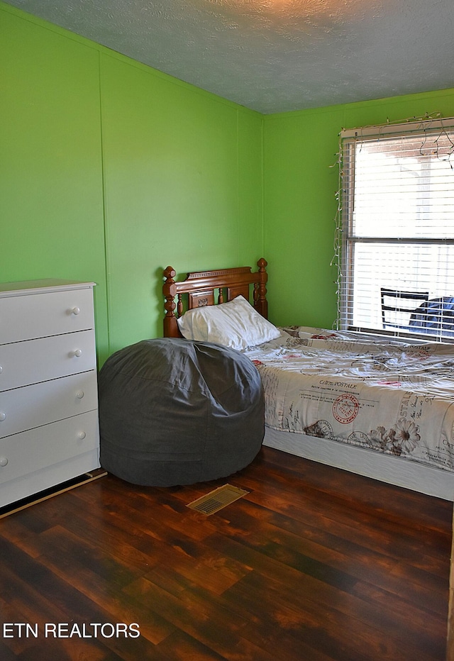 bedroom with dark hardwood / wood-style floors and a textured ceiling