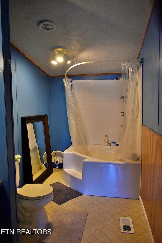 bathroom featuring wooden walls, toilet, shower / tub combo, and a textured ceiling