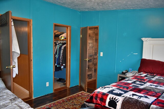 bedroom featuring dark hardwood / wood-style floors, a walk in closet, a closet, and a textured ceiling