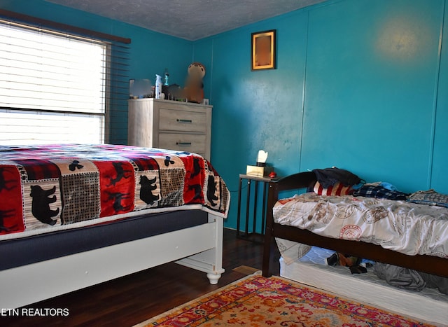 bedroom featuring dark hardwood / wood-style flooring and a textured ceiling