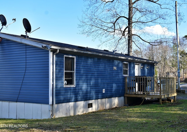 view of side of home with a wooden deck and a yard